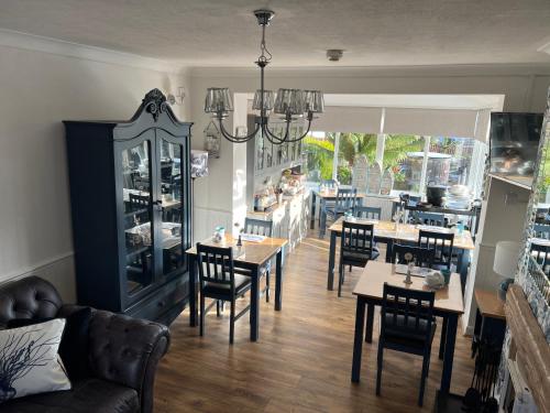 a dining room with tables and chairs and a kitchen at Downsfield Bed and Breakfast in St Ives