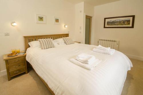 um quarto com uma grande cama branca com toalhas em Farra Grain, Little Langdale em Little Langdale