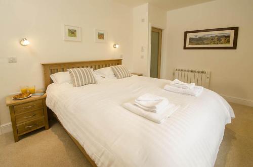 a bedroom with a large white bed with towels on it at Farra Grain, Little Langdale in Little Langdale