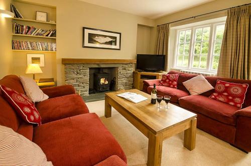 a living room with red couches and a fireplace at Farra Grain, Little Langdale in Little Langdale