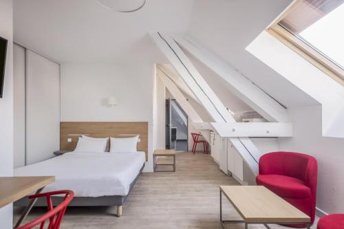 a bedroom with a bed and a red chair at Residhotel Le Central'Gare in Grenoble