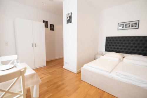 a white bedroom with a white bed and a table at Charming Apartments Frankfurt City in Frankfurt