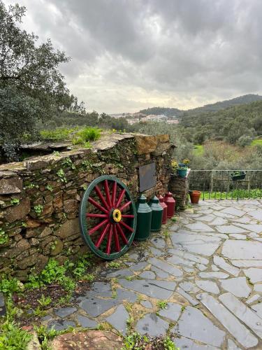 a stone wall with a red wheel next to a stone wall at Quinta Castanheiro da Penha - Alegrete - Portalegre - Alentejo in Alegrete