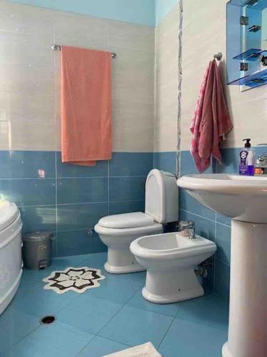 a blue bathroom with a toilet and a sink at Villa Uklala in Kamëz