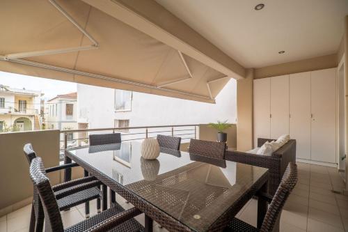 a dining room with a glass table and chairs on a balcony at City Beach Apartment in Chania