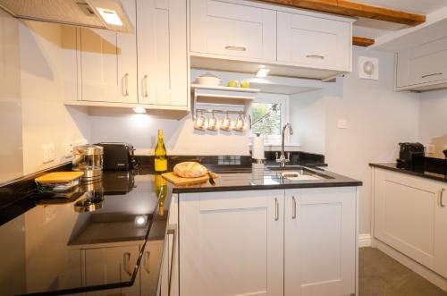 a kitchen with white cabinets and a black counter top at Cherry Tree Cottage in Chapel Stile