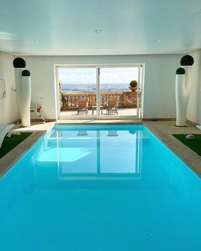 une grande piscine bleue dans une maison dans l'établissement Cabane Spa Sauna, à Ville-sur-Jarnioux