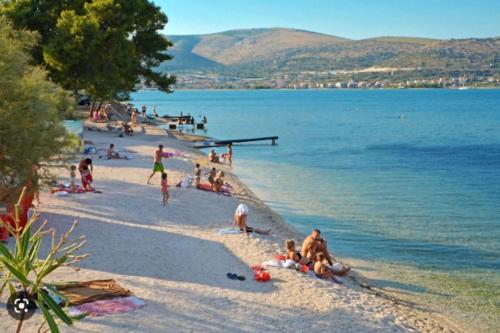 a group of people on a beach near the water at Apartment Tina, Modern, Private SeaView Outdoor Terrace, BBQ, close to beach, 2 bedrooms in Trogir