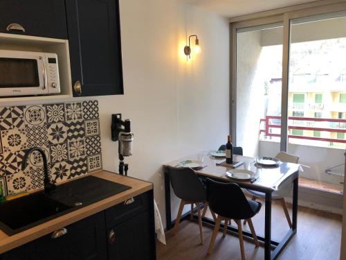 une cuisine avec une table avec des chaises et un micro-ondes dans l'établissement Appart au cœur de la ville (vue montagne), à Cauterets