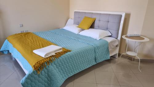 a bed with a blue and yellow blanket and a table at Nice Studio Near The Sea in Ras al Khaimah