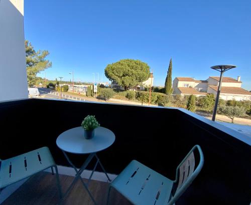 a table and two chairs on a balcony with a view at Les Loges de la Mer - Pérols in Pérols