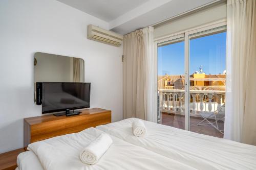 1 dormitorio con 1 cama, TV y ventana en Don Juan apartment with pool in Carvajal Ref 98, en Fuengirola