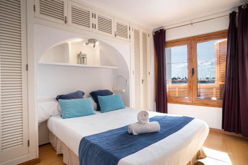ein Schlafzimmer mit einem großen Bett mit blauen Kissen und einem Fenster in der Unterkunft CARABELA 92 in Alcúdia