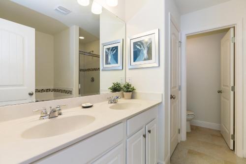 a white bathroom with two sinks and a mirror at Solterra Resort - 6 Bed SOUTH FACING Pool Home - Clubhouse, Resort Pool & Cabanas by Orlando Holiday Rental Homes LLC 5423 in Davenport