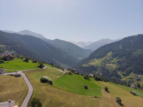 a green field with a road and mountains in the background at Apartment Urgbach Apart-1 by Interhome in Landeck