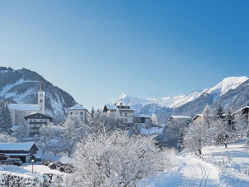 a village covered in snow with mountains in the background at Holiday Home Riki by Interhome in Bruck an der Großglocknerstraße