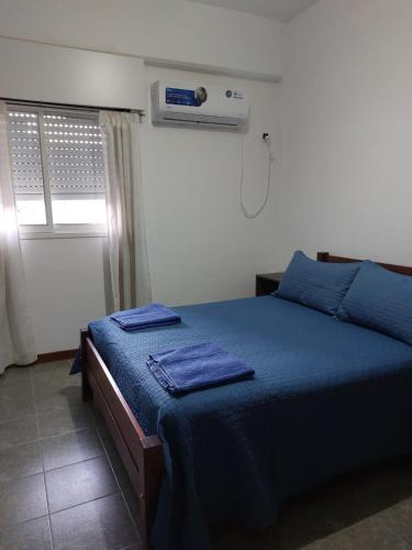 1 dormitorio con cama con sábanas azules y ventana en Departamento a 10 metros de la Catedral y plaza principal, con vista desde el balcon en San Fernando del Valle de Catamarca