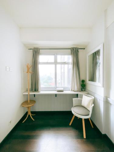 a living room with a chair and a window at The Satu Stay - Apartemen SGV in Tangerang