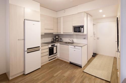 a kitchen with white cabinets and a white refrigerator at First Aparthotel Dasher in Rovaniemi