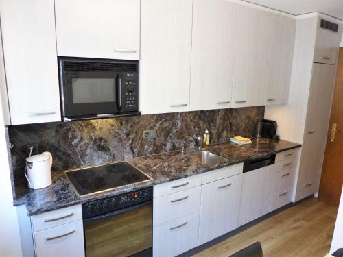 eine Küche mit weißen Schränken, einer Spüle und einer Mikrowelle in der Unterkunft Apartment Vermala-Soleil A-B-4 by Interhome in Vermala