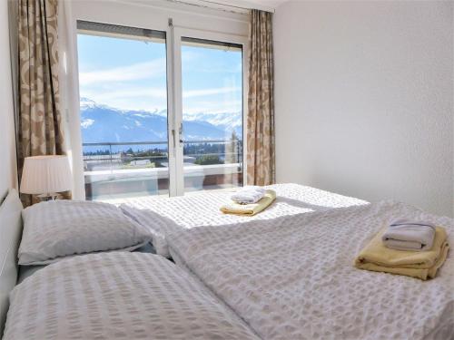 a bedroom with two beds and a large window at Apartment Jeanne d'Arc-5 by Interhome in Crans-Montana