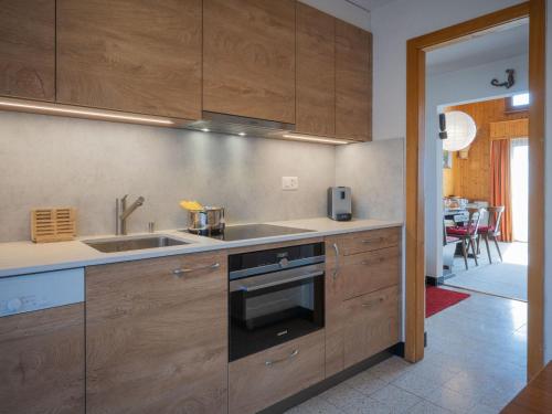 een keuken met houten kasten en een wastafel bij Apartment Plein Soleil A 10 by Interhome in Ovronnaz
