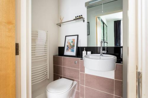 a bathroom with a sink and a toilet and a mirror at Beautiful City Centre Flat with Free Parking in Exeter