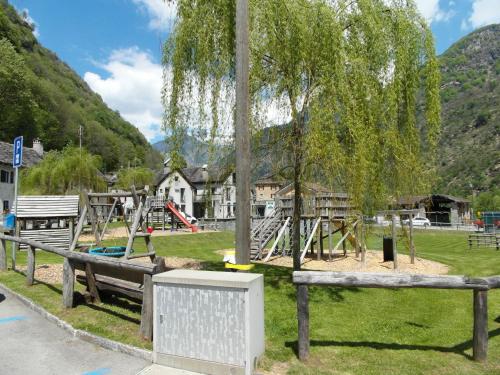 a playground in a park with a tree and swings at Holiday Home Maria by Interhome in Brione