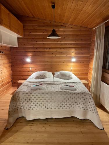 - une chambre avec un grand lit dans un mur en bois dans l'établissement Ruka, Kelokaltiokylä, Mökki 28, à Ruka
