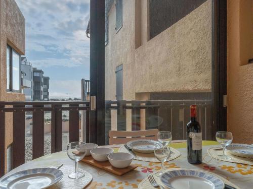 a table with plates and wine glasses on a balcony at Apartment Les Maisons de l'Océan-9 by Interhome in Lacanau-Océan