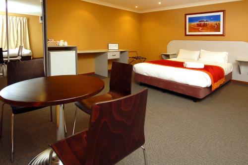 1 dormitorio con cama, escritorio y mesa en Victoria Hotel Strathalbyn, en Strathalbyn