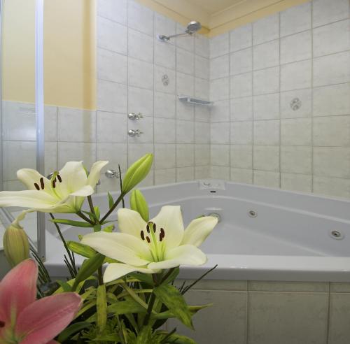 a bathroom with a tub with flowers in front of it at Victoria Hotel Strathalbyn in Strathalbyn