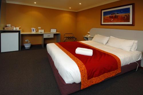 a bedroom with a large bed and a desk at Victoria Hotel Strathalbyn in Strathalbyn