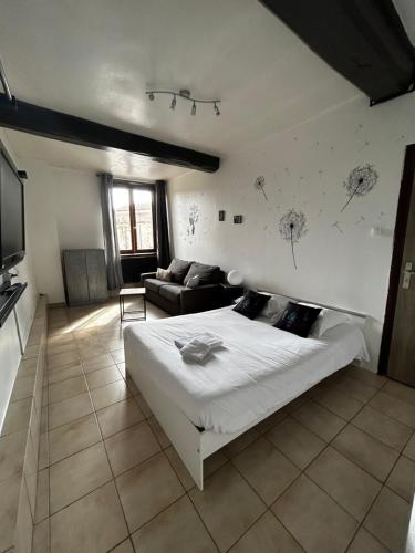 a bedroom with a large white bed and a couch at Hotel de la Place in Loyettes