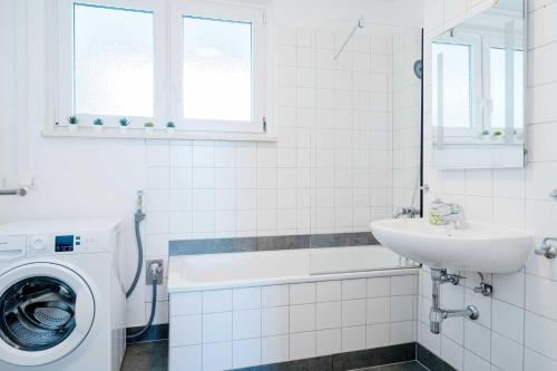 a white bathroom with a sink and a washing machine at Chic City-View Apartments in Hanau in Hanau am Main