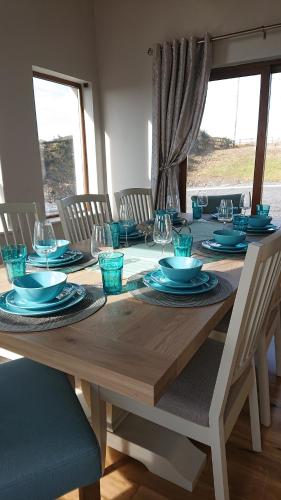 a wooden table with blue plates and glasses on it at Melroche House Doolin in Doolin