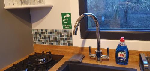 a kitchen sink with a bottle of cleaning detergent next to a stove at Peppercorn Pod at Beck House Glamping in Salmonby