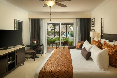 a bedroom with a large bed with a flat screen tv at Jewel Palm Beach in Punta Cana