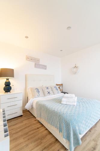 a white bedroom with a bed and a night stand at The Pearl Suite by Margate Suites in Margate