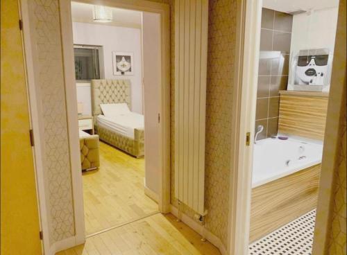 a room with a bathroom with a tub and a bedroom at Designer Penthouse with Riverviews - G1 Glasgow City Centre, 3 Bedrooms, 2 Bathrooms, 1 Living room / Kitchen. Full Floor, Wrap Around Terrace, Panoramic Views, Off Central Station / Buchanan Street in Glasgow