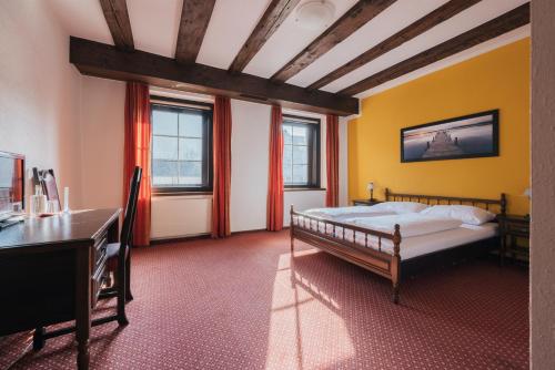 a bedroom with a bed and a desk and windows at Hotel Bären in Feldkirch