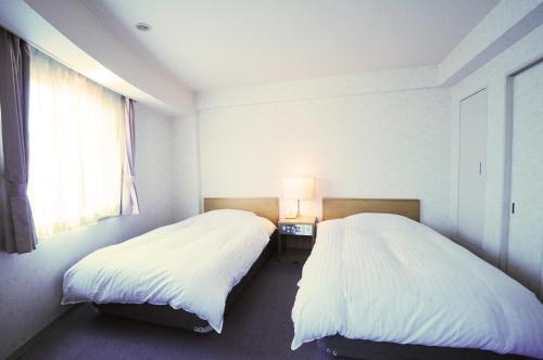 2 Betten nebeneinander in einem Zimmer in der Unterkunft Hotel Saharin in Wakkanai