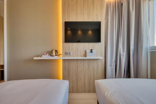 a room with two beds and a tv on a wall at Holiday Inn Express - Madrid - Airport, an IHG Hotel in Madrid