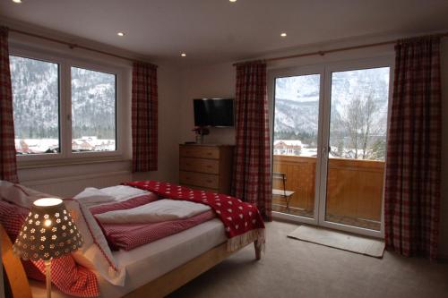 Schlafzimmer mit einem Bett, einem TV und Fenstern in der Unterkunft Haus Salzkammergut in Obertraun