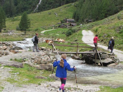 a woman walking over a bridge over a river at Landhotel Häuserl im Wald in Gröbming