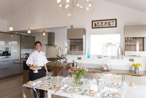 a woman in a kitchen holding a plate of food at Dreamcatchers in Truro