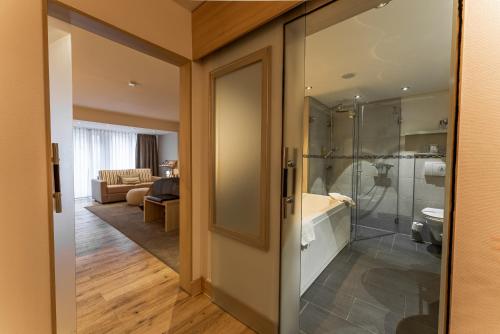 uma casa de banho com uma cabina de duche ao nível do chão e uma porta de vidro em Hotel An der Wasserburg em Wolfsburg