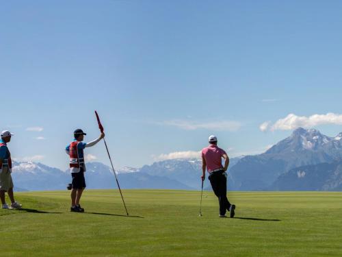 クランにあるApartment Appart-Hotel Helvetia Intergolf by Interhomeの山を背景にした野原で三人のゴルフをしている