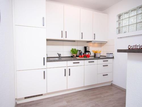een witte keuken met witte kasten en een spoelbak bij Holiday Home Butzel by Interhome in Norddeich