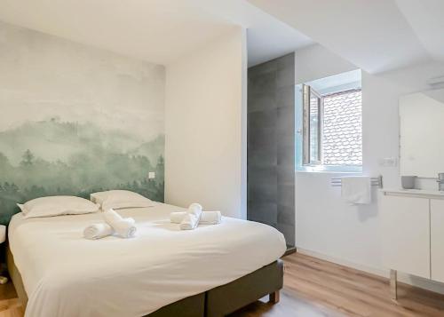 Un dormitorio con una gran cama blanca con toallas. en Rainbow, rue carnot, en Annecy